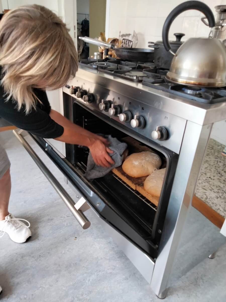 Ineke haalt brood uit oven tijdens workshop zuurdesembrood bakken